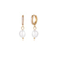 Gold huggie hoop earrings with pavé crystals and white freshwater pearl drops on cream background