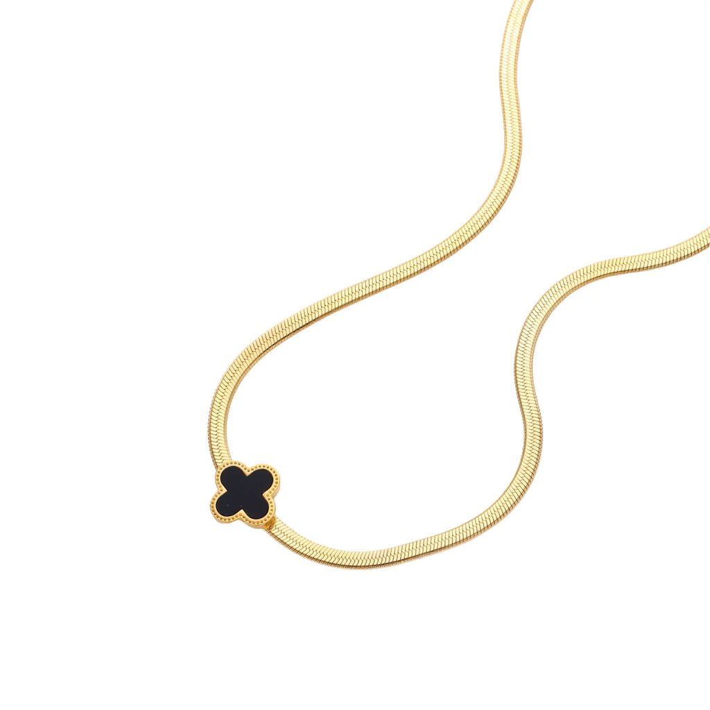 Dainty 18K gold-plated herringbone chain necklace with black enamel quatrefoil clover pendant on white background