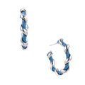 White gold-plated hoops intertwined with blue denim fabric in a twisted rope design on cream background.