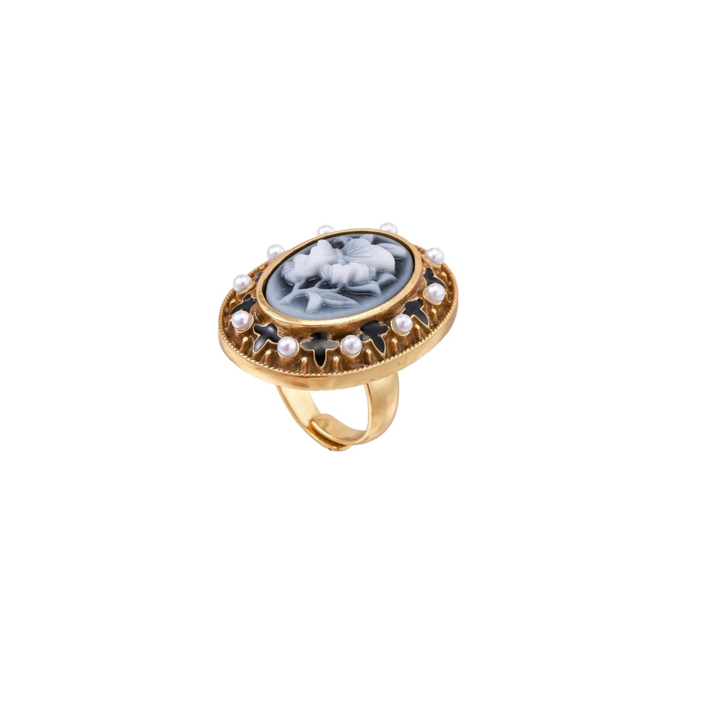 Gold-plated ring with oval blue floral cameo, pearl accents, and black enamel detailing on white background.