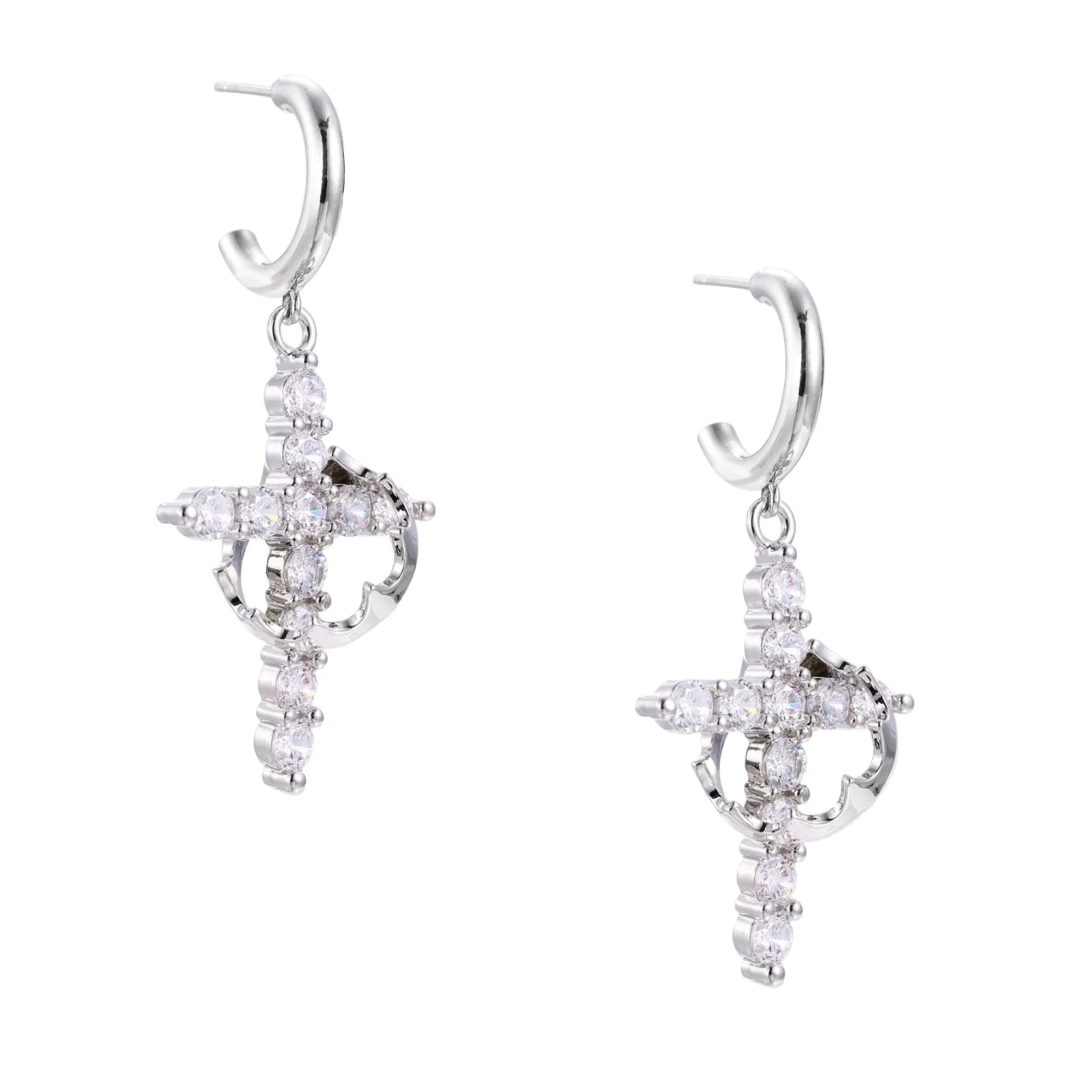 White gold-plated hoop earrings with sparkling zirconia cross charms dangling against cream background
