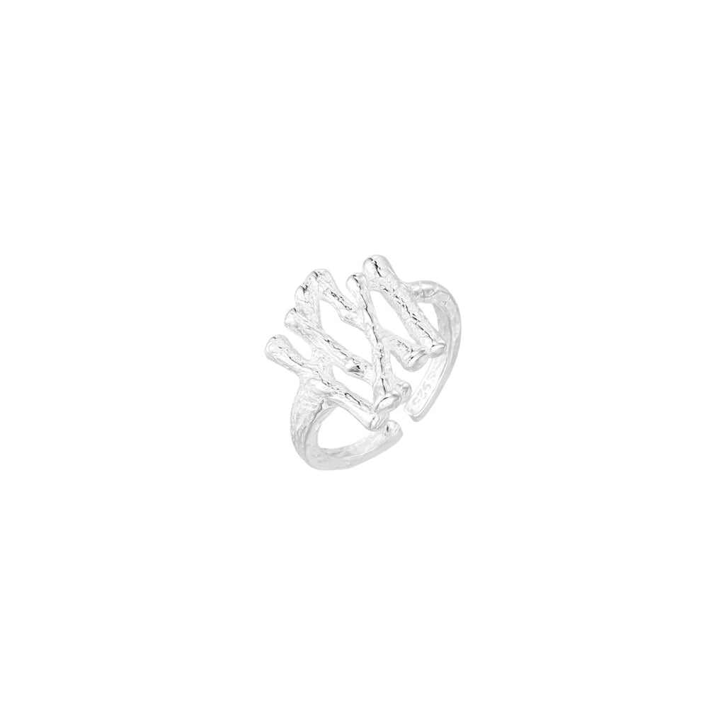 Sculptural sterling silver ring with organic branch design and textured surfaces on cream background