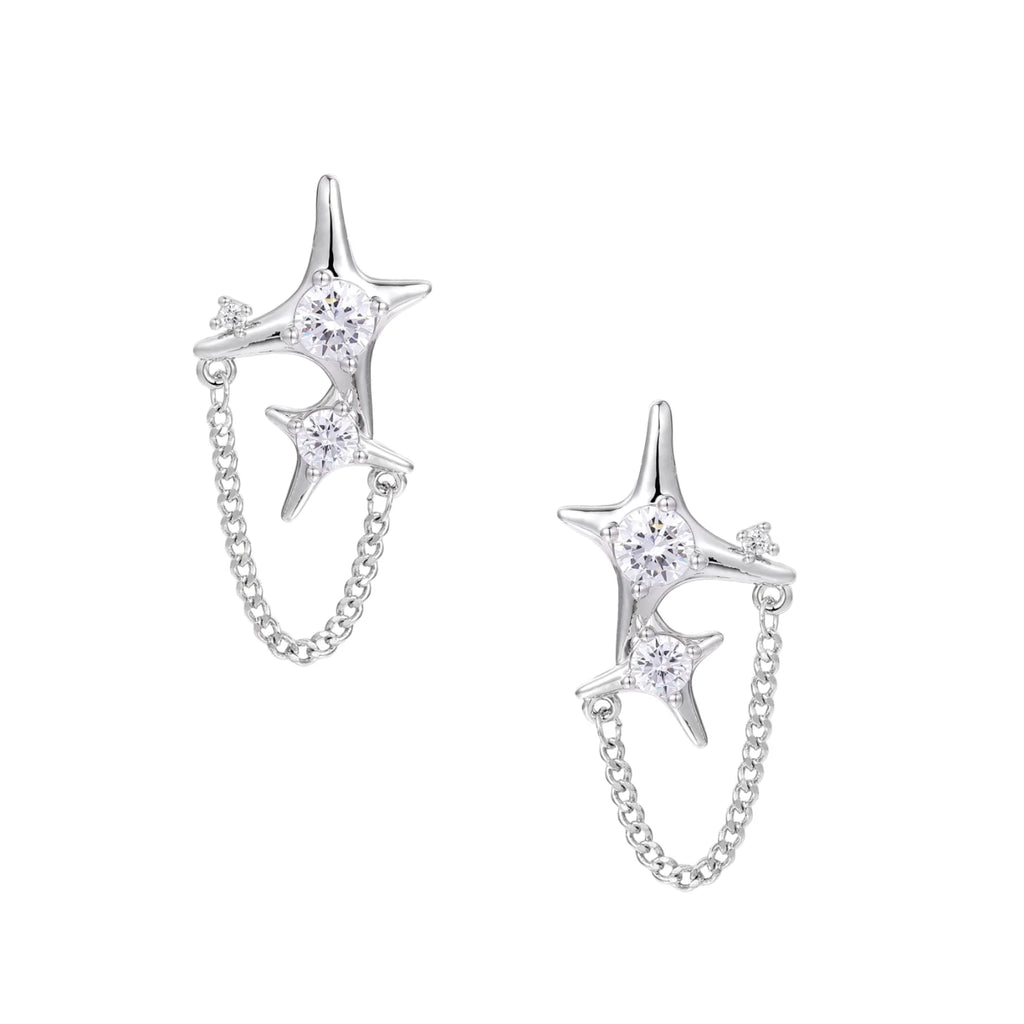 Silver star studs with crescent moon cutouts and zirconia stones connected by delicate chains on white background