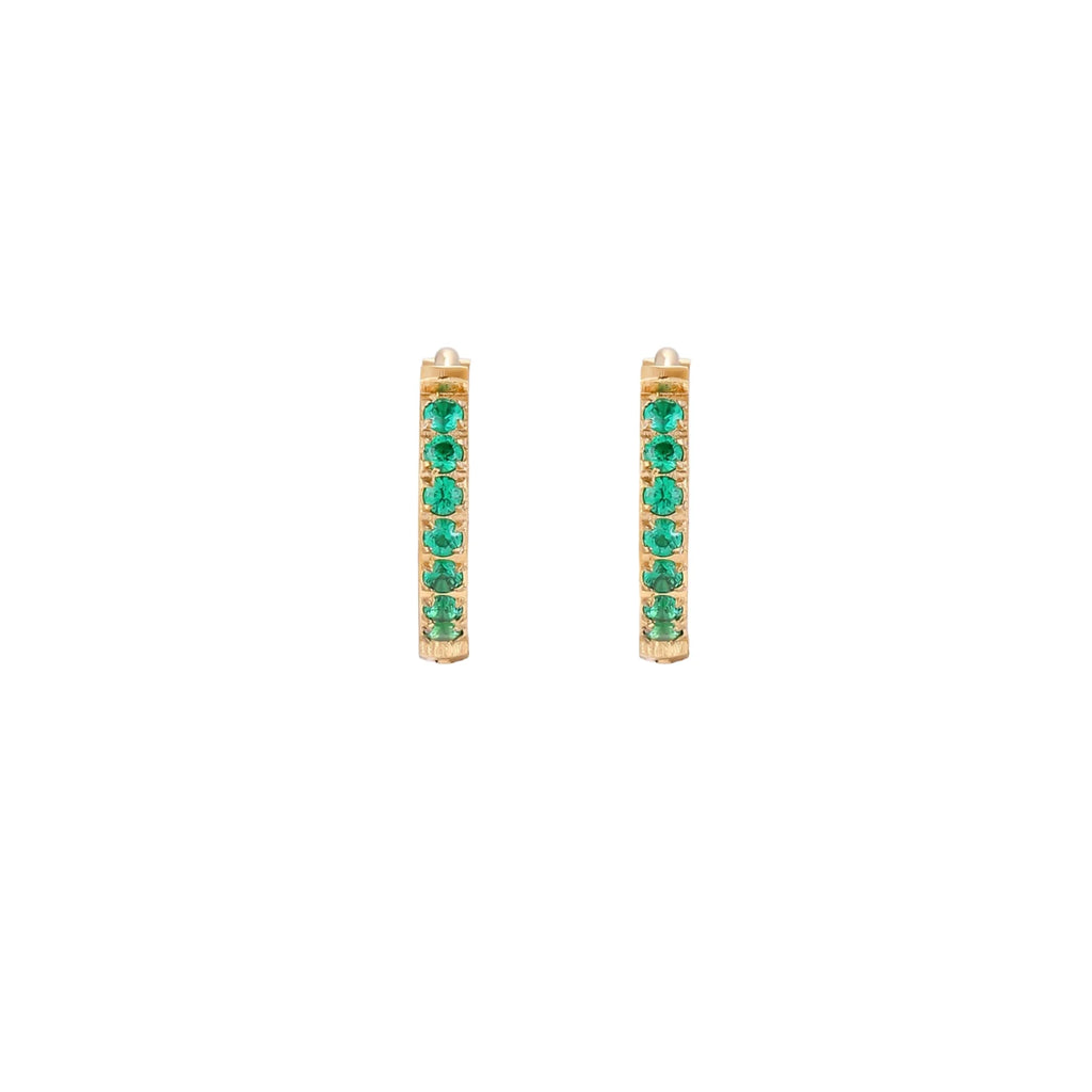 Pair of small gold huggie hoop earrings with bright green cubic zirconia stones on cream background