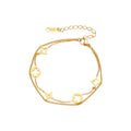 Double-layer gold-plated bracelet with quatrefoil and star charms on cream background, 18K gold finish.